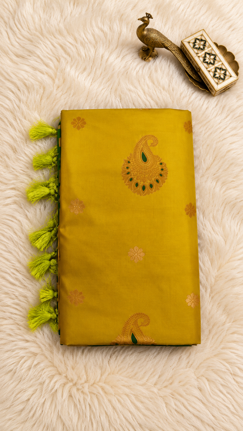 Mustard yellow soft silk saree with gold zari paisley butta and green tassels
